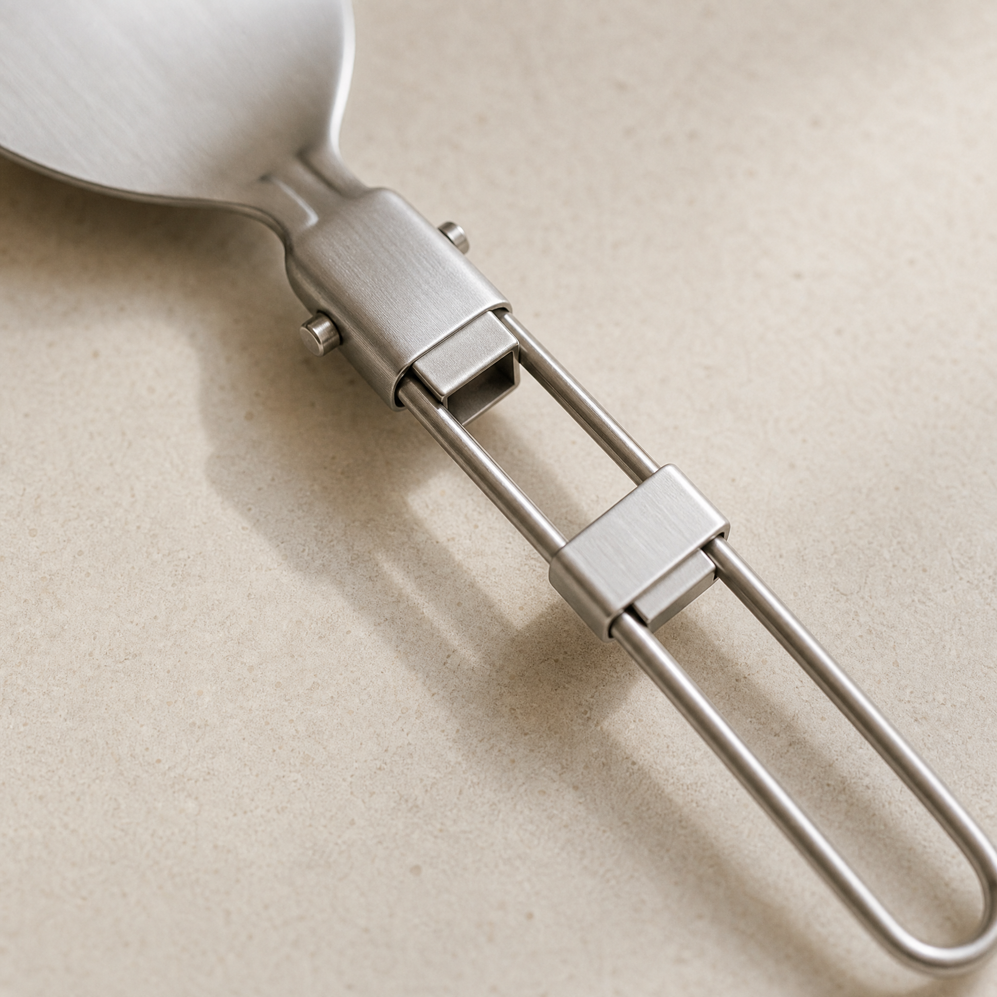 Close-up of the folding hinge and sliding lock collar on a Verano stainless steel utensil handle